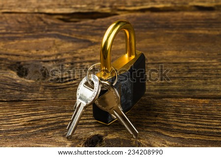 hinged lock with keys on wooden background