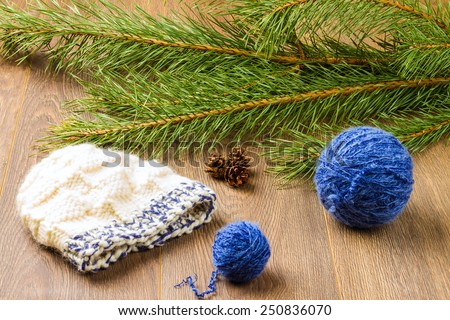 ball of threads, knitting cap, pine-cones and branch of  pine on wooden background