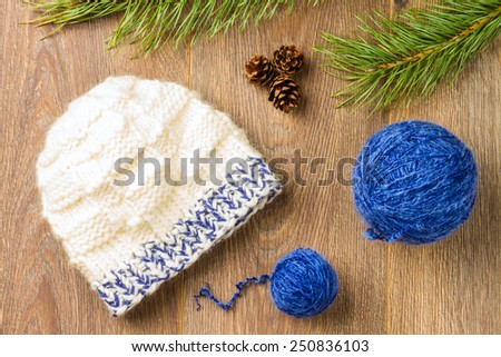 ball of threads, knitting cap, pine-cones and branch of  pine on wooden background