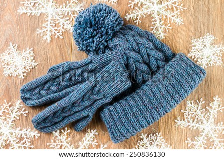 mittens, knitting cap and christmas-tree decorations on wooden background