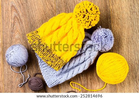 ball of threads and knitting caps on wooden background