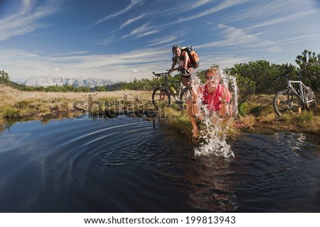 Austria, Salzburger Land, Bikers by lake, man splashing water, laughing, portrait