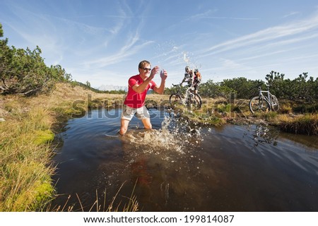 Austria, Salzburger Land, Bikers by lake, man splashing water