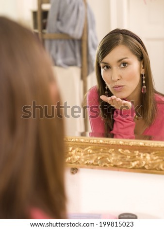 Woman blowing kiss in front of mirror