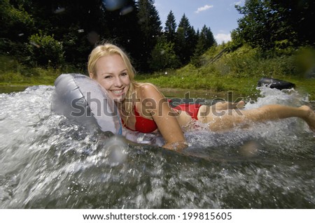 Austria, Salzburger Land, Lake Reitecksee, Young woman on airbed fooling around