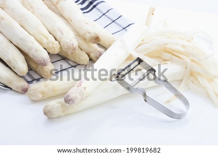 White asparagus and peeler on dish cloth