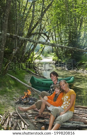 Austria, Salzburger Land, Family sitting at campfire, smiling