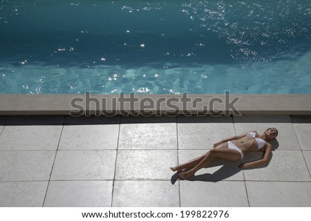 Woman sun bathing at swimming pool