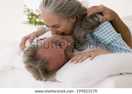 Mature couple embracing in bed laughing
