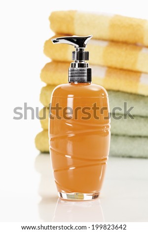 Soap in soap dispenser with stack of towels in background