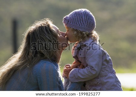 Mother kissing daughter, side view