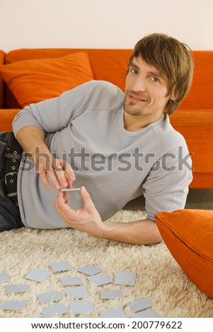 Portrait of a young man in living room playing memory game