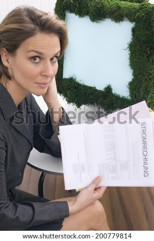 Businesswoman with utility bill sitting in front of computer