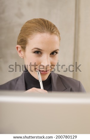 Businesswoman looking at camera holding pen to mouth