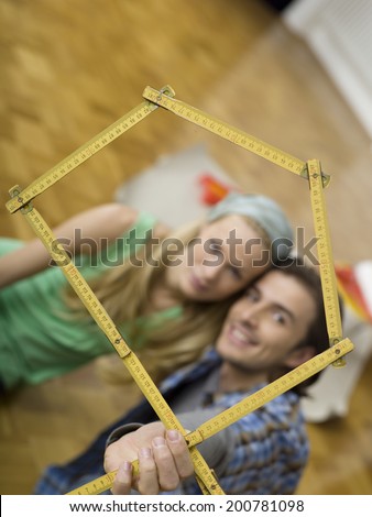 Young couple making house shape with folding rule focus on ruler