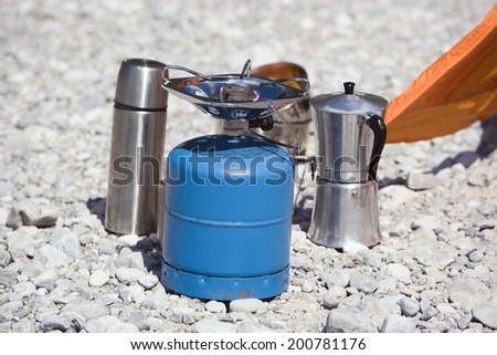 Camping equipment camping stove coffee maker thermos on stony ground