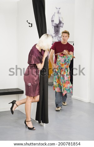 Young woman in changing room, man in background