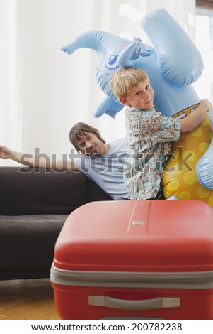 Family preparing for vacation boy playing with inflatable elephant father sitting in background