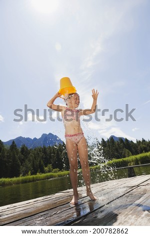 Italy, South Tyrol, girl pouring a bucket of water over her head