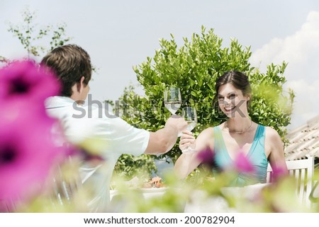 Italy South Tyrol couple in restaurant toasting with white wine smiling