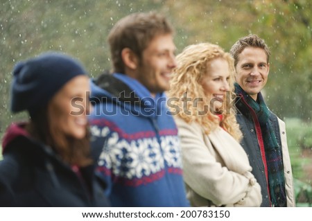 Germany, Bavaria, English Garden friends standing in rainy beer garden smiling