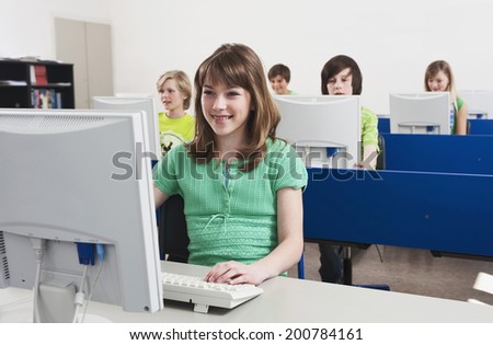 In computing class students using computer girl smiling in front row