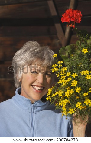 Austria, Senior woman looking at flowers smiling