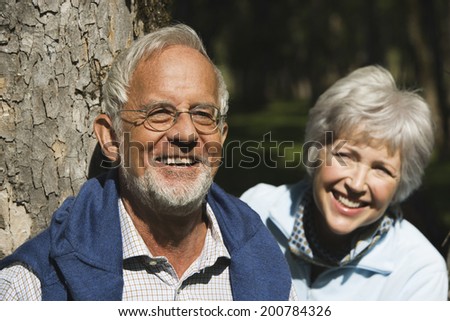 Austria Karwendel senior couple man leaning on tree trunk woman behind smiling close up