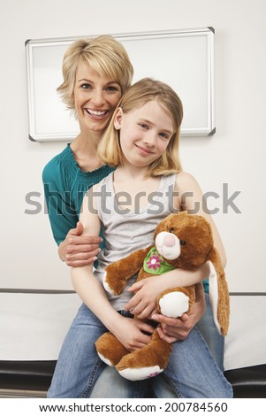 Girl sitting on mother\'s lap both smiling close up