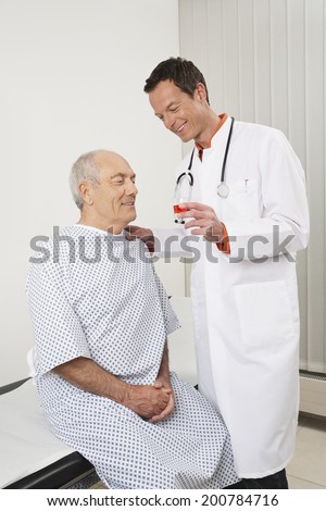 Doctor talking to patient at hospital giving elderly man his medication