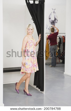 Young woman in changing room, man in background