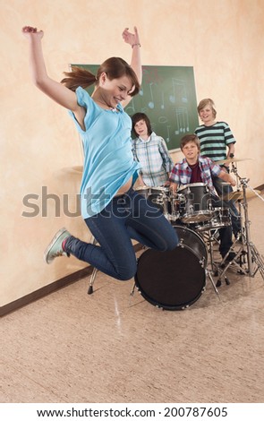 Students at music class girl jumping boy playing drums classmates standing behind
