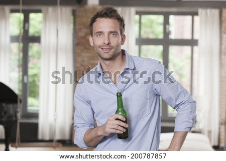 Germany, Man standing and holding beer bottle, portrait