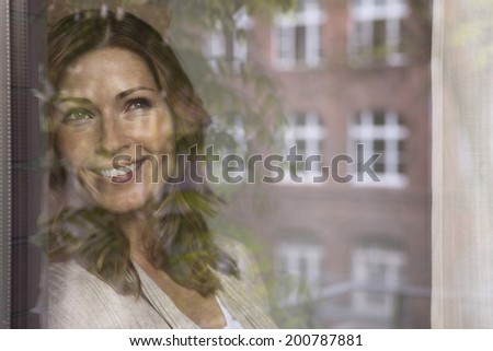 Germany, Woman looking out the window smiling