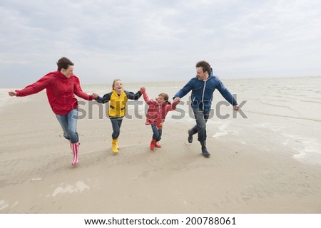 Germany, St. Peter-Ording, North Sea family holding hands and running on beach