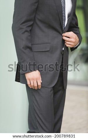 Businessman adjusting his jacket middle section