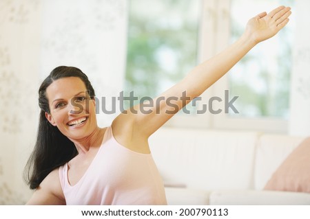 Attractive young woman doing fitness exercise bending arm stretched out smiling