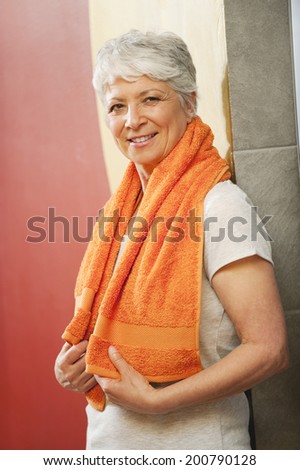 Senior woman in changing room with towel round shoulders smiling