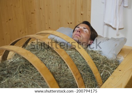 Man having hay bath lying on a pillow
