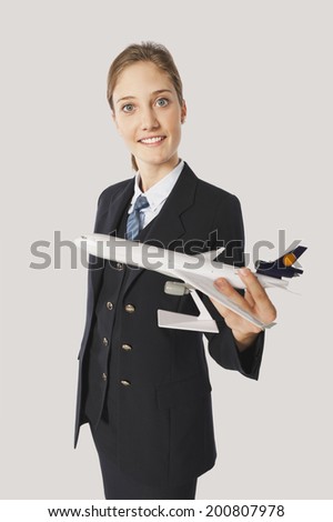 Young air hostess with model airplane on white background