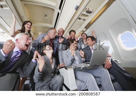 Group of passengers looking at laptop on airplane