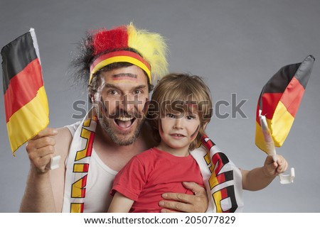 German soccer fans, father and son cheering together both holding german flags