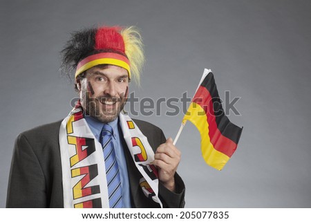 Businessman as german soccer fan holding german flag in hand