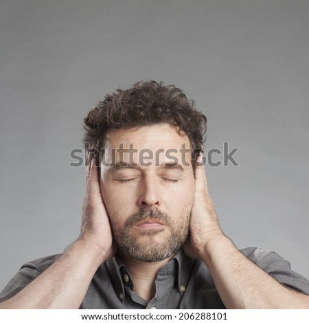 Mature man covering ears with hands