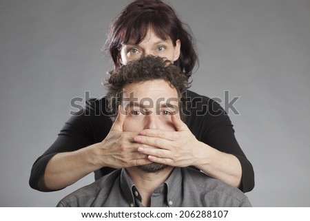 Mature couple woman covering man\'s mouth
