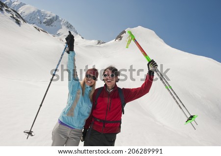 Austria, Salzburger Land, Altenmarkt, Zauchensee, Young couple holding ski poles, cheering