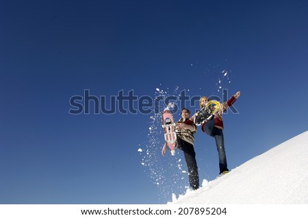Young couple splashing snow with snow shoes, low angle view