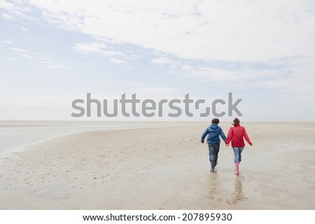 Germany, St. Peter-Ording, North Sea, Couple holding hands and walking on beach