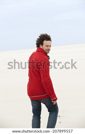 Germany, St Peter-Ording, North sea, Man walking in sand dunes looking back rear view
