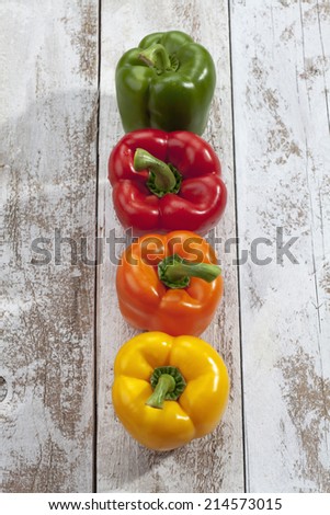 Red yellow orange green bell peppers on wooden table, high angle view